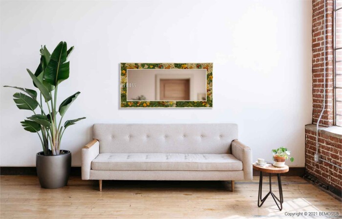 ein Wohnzimmer mit einer Couch und einem Spiegel an der Wand darüber und einer Pflanze in einem Topf, moosbild, mooswand, moos pflanzen, moos, moos deko, moos art