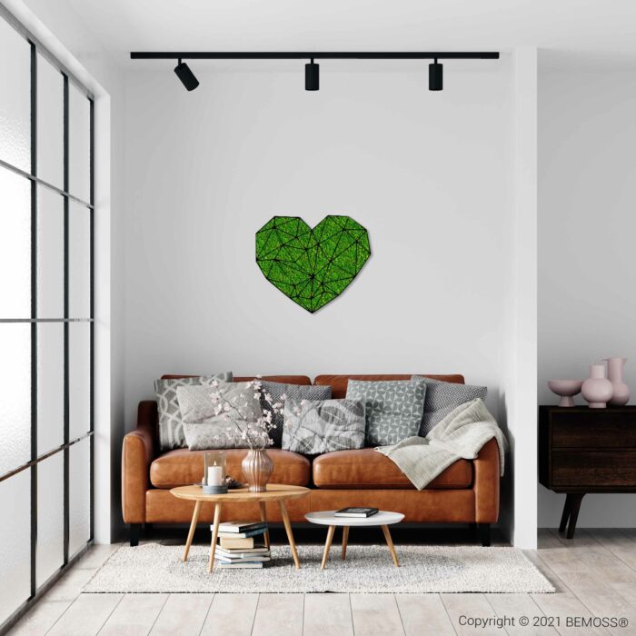 ein Wohnzimmer mit einer Couch und einem Tisch mit einem grünen Herzen an der Wand über einem Couchtisch, moosbild, mooswand, moos pflanzen, moos, moos deko, moos art