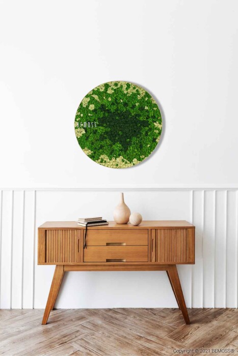 Eine grüne Pflanze steht an einer Wand über einem Holztisch mit einer Vase darauf und einer weißen Wand dahinter, moosbild, mooswand, moos pflanzen, moos, moos deko, moos art