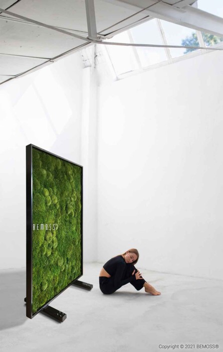 Ein Mann sitzt auf dem Boden vor einem Fernsehbildschirm mit einer Mooswand dahinter und ein Mann sitzt auf dem Boden, moosbild, mooswand, moos pflanzen, moos, moos deko, moos art